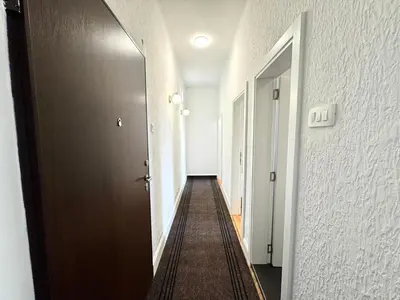 a hallway with a door and a long hallway at The Government District Suite in Podgorica