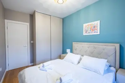 a bedroom with a white bed with blue walls at The Point - Modern City Apartment in Kruševac