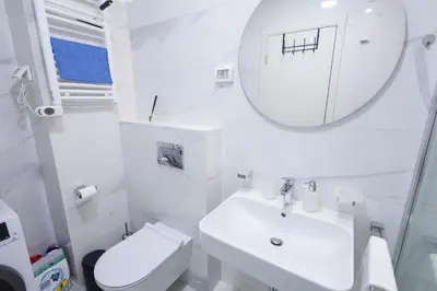 a white bathroom with a sink and a mirror at The Point - Modern City Apartment in Kruševac