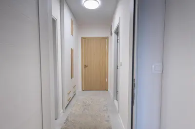 a hallway with white walls and a wooden door at Urban Stay - Central Point Apartment in Kruševac
