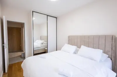 a bedroom with a large white bed and a mirror at Urban Stay - Central Point Apartment in Kruševac