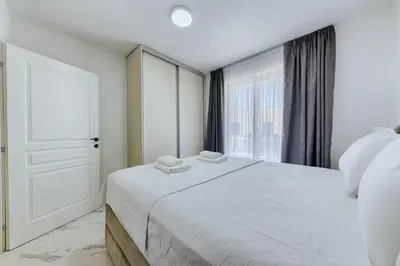 a white bedroom with a large bed and a window at Malik Bay RESIDENTS in Bar