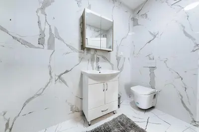 a white bathroom with a sink and a toilet at Malik Bay RESIDENTS in Bar