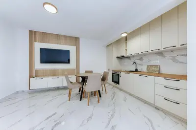a kitchen with white cabinets and a table with chairs at Malik Bay RESIDENTS in Bar