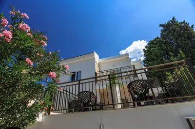 a white house with chairs on a balcony at Riva Lux Apartments in Sutomore