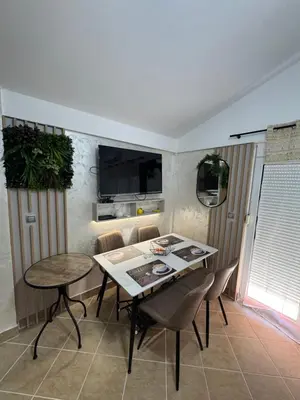 a dining room with a table and chairs and a tv at Apartman Sunce in Budva