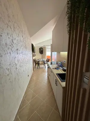 a kitchen with white cabinets and a tile floor at Apartman Sunce in Budva