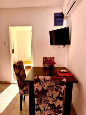 a dining room table and chairs with a television on the wall at Adriatic Stay Apartments in Budva