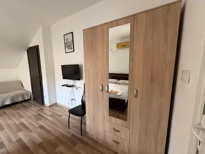 a bedroom with a wooden door with a bed and a desk at Solis Apartments Sutomore in Sutomore