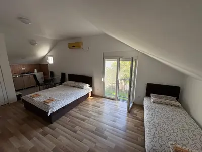a bedroom with two beds and a kitchen with a table at Solis Apartments Sutomore in Sutomore