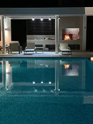 a swimming pool with two chairs and a fireplace at Villa Jelena in Reževići
