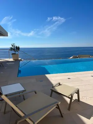 a swimming pool with a chair and a table at Villa Jelena in Reževići