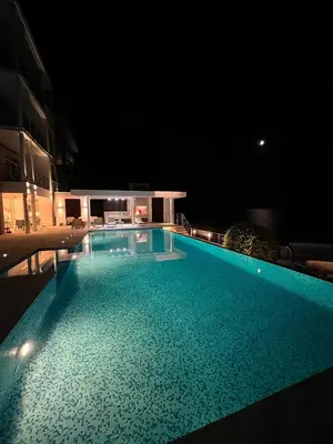 a large swimming pool at night with a building at Villa Jelena in Reževići