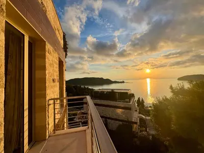 a balcony with a view of the ocean at sunset at Exclusive Luxury Villa in Dukley Gardens in Budva