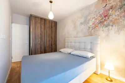 a bedroom with a bed and a painting on the wall at Fratello Apartment in Podgorica