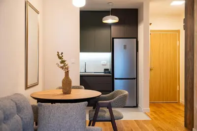 a living room with a table and chairs and a kitchen at Fratello Apartment in Podgorica