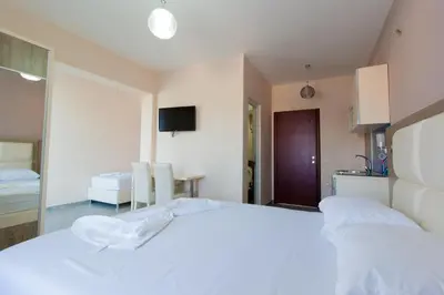 a bedroom with a white bed and a kitchen at A3 Apartments in Ulcinj