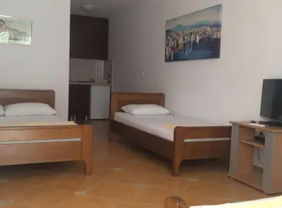 a bedroom with two beds and a tv and a desk at Apartments Aleksić, Bečići in Becici