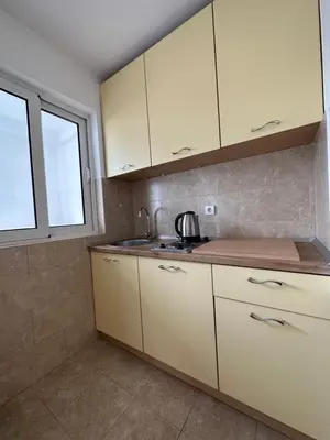 a kitchen with white cabinets and a sink and a window at Apartmani Bulevar Budva in Budva
