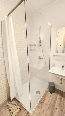 a white bathroom with a shower and a sink at Central Light Apartment in Podgorica