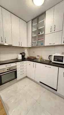 a kitchen with white cabinets and a microwave at Central Light Apartment in Podgorica