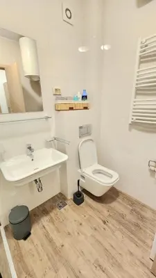 a white bathroom with a toilet and a sink at Central Light Apartment in Podgorica