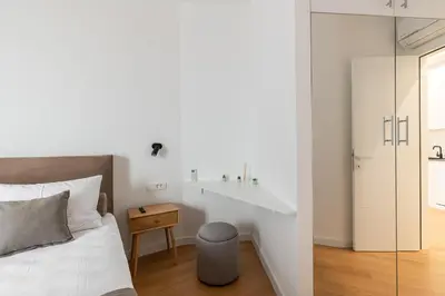 a bedroom with a bed and a table and a stool at Stunning Bečići Apartment in Becici