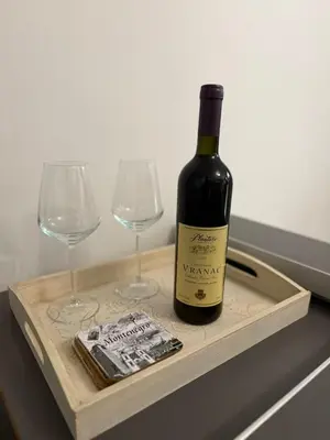 a bottle of wine on a wooden tray with two wine glasses at Kutak in Podgorica