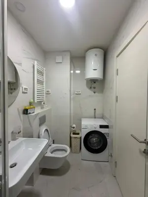 a white bathroom with a washing machine and a sink at Oaza Bar 1 in Bar