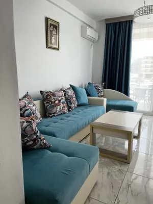 a living room with a blue couch and a table at Bilali Apartments in Ulcinj