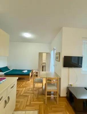 a room with a kitchen and a living room with a table at ADAIST Apartments Budva Free Parking & Balcony in Budva