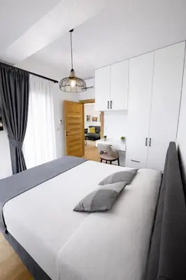 a bedroom with a large white bed and a living room at Olive apartments in Petrovac na Moru