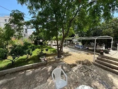 a white chair sitting under a tree in a park at Radon apartments in Dobra Voda