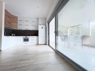 a kitchen with white cabinets and a large sliding glass door at Flat in Budva with terrace and private garden in Budva
