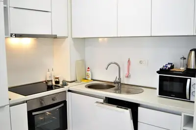 a kitchen with white cabinets and a sink and a microwave at Yeshill Deluxe Apartment in Budva
