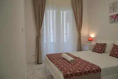 a bedroom with a bed with a red and white comforter at Yeshill Deluxe Apartment in Budva