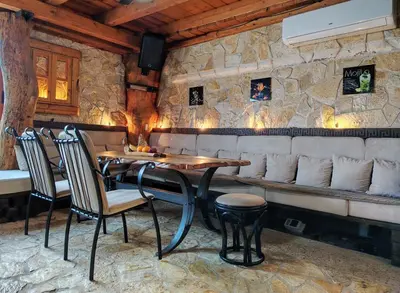 a restaurant with a table and chairs and a stone wall at Hedonizam Lux in Podgorica