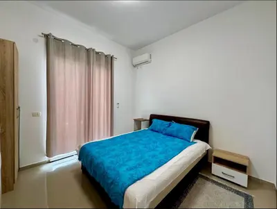 a bedroom with a bed with blue sheets and a window at Bar Lux Two-Bedroom apartment in Bar