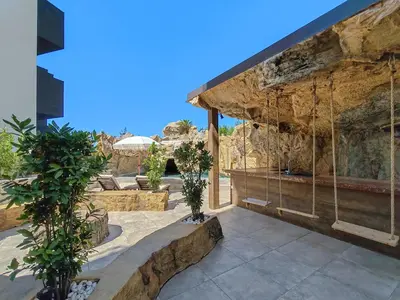 an outdoor patio with a stone wall and swings at Serenity Apartment in Becici