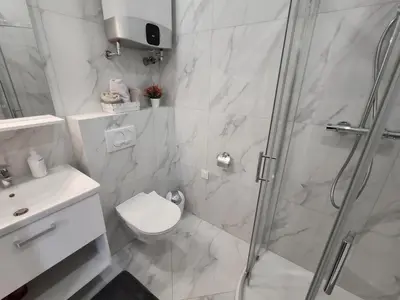 a white bathroom with a shower and a toilet at Serenity Apartment in Becici