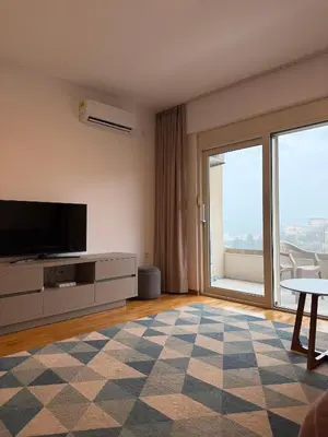 a living room with a tv and a large window at Status Complex in Becici