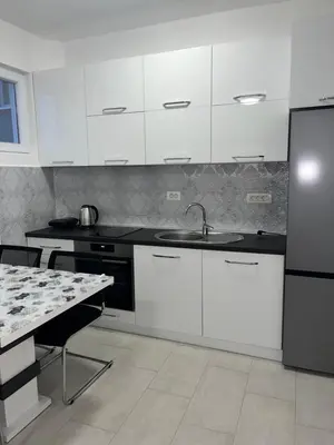 a kitchen with white cabinets and a sink and a table at Sun Stay in Bar