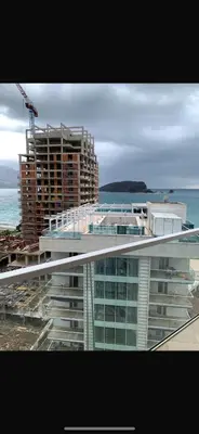 a view of a building with the ocean in the background at Vista Deluxe apartment - Tre Canne Budva in Budva