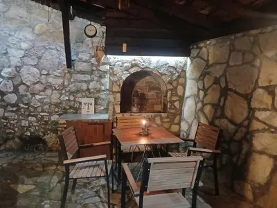 a table and chairs in a room with a stone wall at Kapa's House in Cetinje