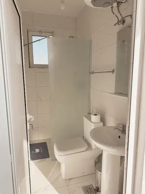 a white bathroom with a toilet and a sink at Gzim Peja in Ulcinj