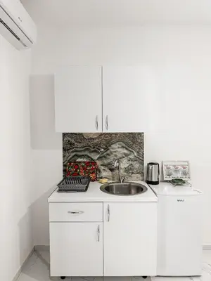 a kitchen with white cabinets and a sink at Gzim Peja in Ulcinj
