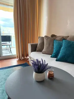 a living room with a couch and a table with purple flowers at Seaview Rafailovici in Rafailovici