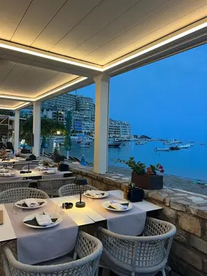 a restaurant with tables and chairs with a view of the water at Seaview Rafailovici in Rafailovici