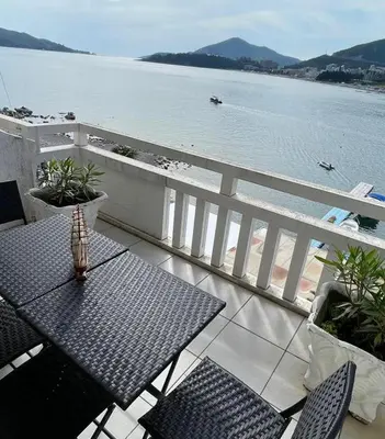 a table and chairs on a balcony with a view of the water at Seaview Rafailovici in Rafailovici