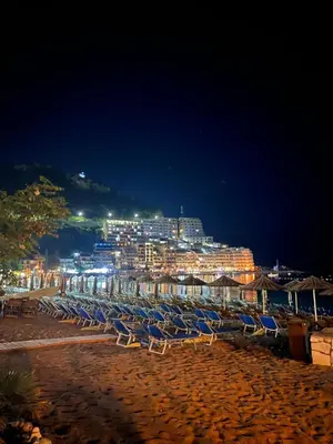 a group of chairs and umbrellas on a beach at night at Seaview Rafailovici in Rafailovici